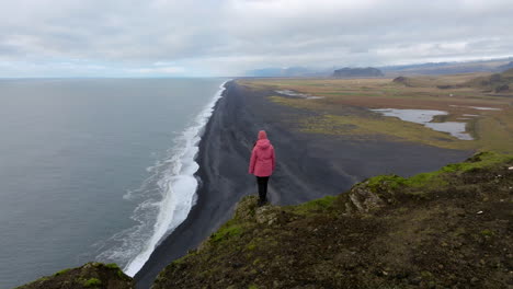 Levantándose-Sobre-Una-Mujer-Parada-Sobre-Un-Acantilado-En-El-Mirador-De-Dyrholaey-En-Islandia