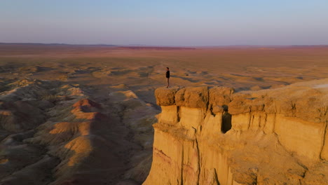 Männlicher-Tourist,-Der-Während-Des-Sonnenuntergangs-Auf-Der-Klippe-Am-Tsagaan-Suvarga-White-Stupa-Der-Mongolei-Steht---Drohnenaufnahme
