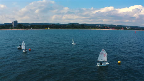 Panoramic-view-of-Optimist-dinghy-boats-sailing-on-the-baltic-sea-near-Sopot-city-at-sunny-vacation-day