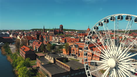 Drone-flying-arond-the-Ferris-Wheel-in-Gdańsk-with-old-town-and-tenements-in-the-background-at-sunny-summer-day