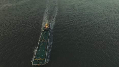 Epic-aerial-view-of-cargo-ship-sailing-on-the-Hudson-River-at-sunset,-United-States
