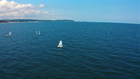 Aerial-view-of-Optimist-dinghy-boats-sailing-on-the-blue-waters-of-baltic-sea-in-Sopot,-Poland-at-sunny-vacation-day