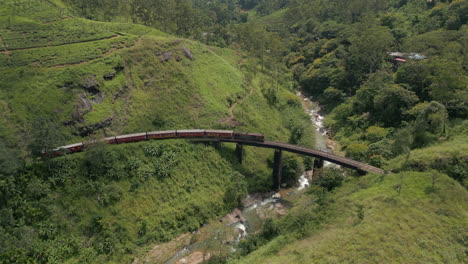 Establishing-Aerial-Drone-Shot-of-Diesel-Passenger-Train-Crossing-Demodara-Iron-Bridge-on-Sunny-Day-in-Sri-Lanka
