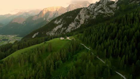Small-hut-on-a-ledge-in-front-of-massive-cliff-during-sunset-in-the-Alps-in-Lofer,-Austria
