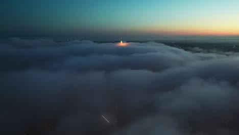 Aerial-flight-over-dense-dark-clouds-in-the-air-above-City-during-sunrise-at-horizon