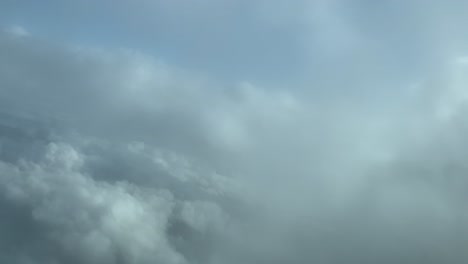 Luftaufnahme-Der-Wolkenkulisse-Aus-Dem-Cockpit-Eines-Flugzeugs-Beim-Flug-über-Einige-Flauschige-Winterklumpen-Mit-Tiefblauem-Himmel