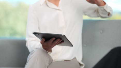 Body-shot-of-woman-with-tablet-explains-business-decisions-in-meeting