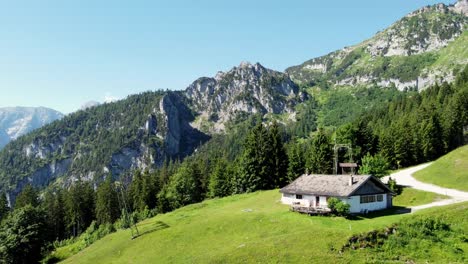 Wunderschöne-Filmische-Luftaufnahme-Eines-Hauses-In-Grünen-Hängen-In-Großer-Höhe-In-Den-österreichischen-Alpen