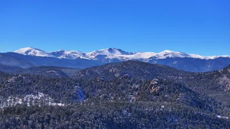 Christmas-first-snow-Evergreen-Three-Sisters-Front-Range-Denver-Mount-Blue-Sky-Evans-aerial-cinematic-drone-crisp-freezing-cold-morning-beautiful-blue-sky-frosted-pine-trees-upward-motion