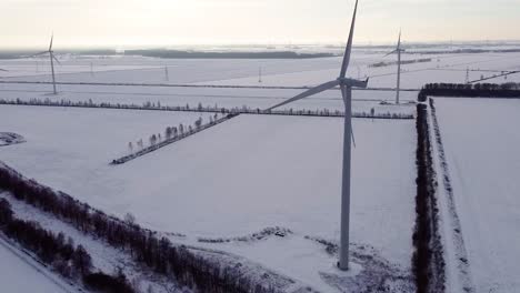 Aerial-view-of-wind-turbine-blade-rotate-in-scenic-snowy-winter-landscape