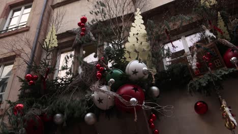 Elaboradas-Y-Hermosas-Decoraciones-Navideñas,-Incluidas-Campanas-Y-Oropel,-En-El-Escaparate-Del-Festivo-Mercado-Navideño-En-Estrasburgo,-Francia,-Europa