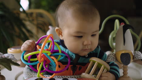 Cute-mixed-race-Asian-baby-playing-and-banging-his-rattle-toys-and-keeping-himself-busy-and-amused