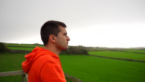 Young-man-looking-at-beauty-of-green-farm-fields-in-Terceira,-Azores