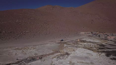 Aerial-following-car-moving-along-the-desolate,-barren-and-beautiful-landscape-in-Bolivia