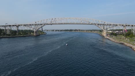 Boat-in-St-Clair-River-with-Blue-Water-Bridge,-Port-Huron-Michigan,-USA