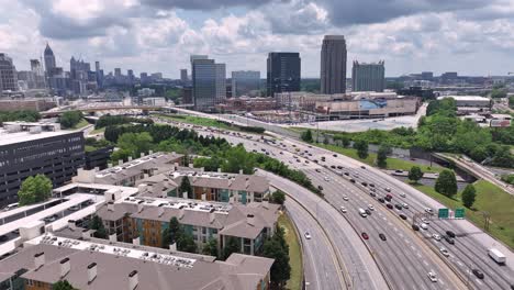 Aerial-of-Atlanta-expressway-moving-traffic-with-modern-skyline-buildings-in-background,-Georgia,-USA