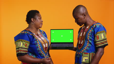 Ethnic-couple-showcasing-laptop-with-greenscreen-display