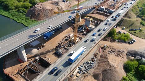 Traffic-jam-occurs-on-highway-bridge-while-constructing-new,-aerial-view