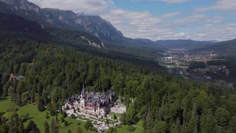 Stunning-Peles-Castle-drone-view,-Romanian-Carpathian-mountains-in-the-background