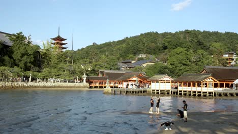 Touristen-Sahen,-Wie-Sie-Am-Itsukushima-Schrein-Mit-Der-Fünfstufigen-Pagode-Im-Hintergrund-Fotos-Von-Der-Flut-Machten