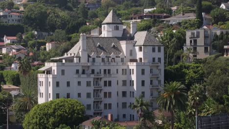 Chateau-Marmont-Hotel,-iconic-celebrity-and-famous-location-on-Sunset-Blvd,-aerial-rising-over-Hollywood-homes