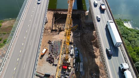 Huge-crane-constructing-bridge-near-Kaunas-over-Neris-river,-aerial-view