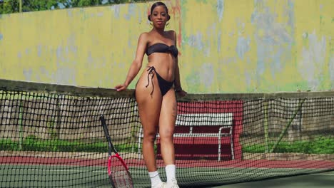 Engaged-in-a-tennis-match-on-a-sunny-day,-a-young-woman-confidently-wears-a-thong-bikini