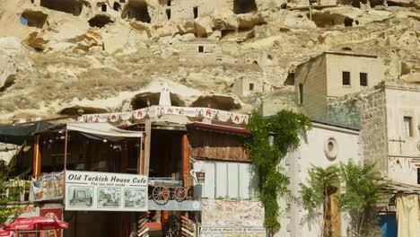 Old-Turkish-cafe-setting-below-amazing-rock-cave-houses-Cappadocia