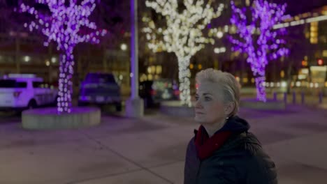 Senior-woman-walking-alone-in-a-city-at-nighttime-during-the-Christmas-season