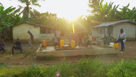 Kinder-Sammeln-Wasser-Und-Spielen-Und-Tanzen-Mit-Einer-Wasserpumpe-In-Einem-Abgelegenen-Dorf-In-Afrika-Bei-Sonnenuntergang