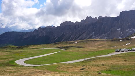 Far-away-unrecognizable-cyclist-cycling-on-uphill-Passo-Giau,-rocky-mountain