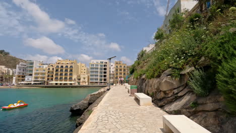 POV-walking-down-a-stone-path-towards-waterfront-hotels-in-Malta