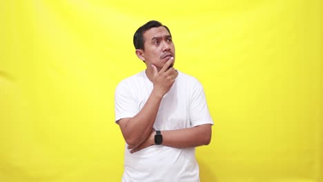 A-handsome-elder-asian-man-is-thinking-about-while-raising-her-finger-coming-up-with-an-idea-isolated-over-a-yellow-wall-in-the-studio