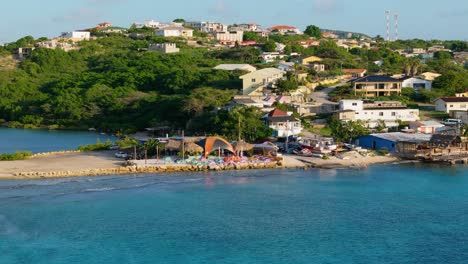 Drone-push-in-as-calm-waves-crash-over-reef-flats-of-Boca-Sami-to-niffo-huts-on-the-coast,-Curacao