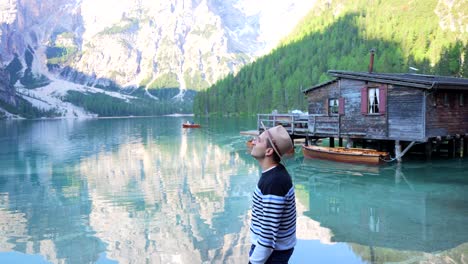 Hombre-Turista-Usa-Sombrero-Mirando-Alrededor-Fascinado-Por-El-Lago-Di-Braies,-Tirol-Del-Sur