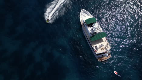 Aerial-Drone-footage-of-Yacht-in-the-Sea-during-summer-jet-ski-passing