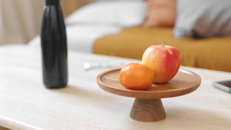Person-picks-mandarin-from-modern-minimalist-table-in-cozy-apartment