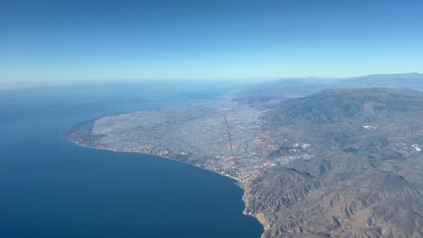 A-sea-of-plastic-in-El-Ejido,-Almeria,-the-biggest-greenhouses-area-in-Europe,-shot-from-an-airplane-cabin-in-a-splendid-bright-and-sunny-sky