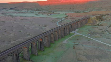 Moorland-hill-illuminated-by-winter-sunrise-light-and-viaduct-arches-catching-light