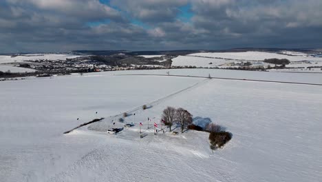 Die-Kamera-Schwenkt-Vom-Gipfel-Weg-Zwischen-Schneebedeckten-Feldern-Mit-Hügeln-Im-Hintergrund
