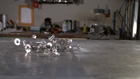Screws,-washers-and-nuts-falling-in-on-a-metal-worker’s-table-in-super-slow-motion