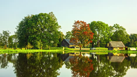 Bauernhaus-An-Einem-See-Im-Herbst---Zeitraffer-Symmetrie-In-Der-Spiegelung-Auf-Der-Wasseroberfläche