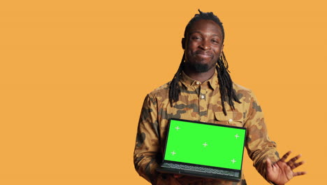 Young-guy-showing-pc-with-greenscreen-layout-on-camera,