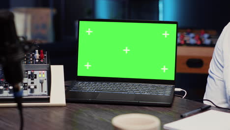 Close-up-of-green-screen-laptop-next-to-podcast-microphone