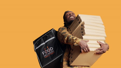 Young-deliveryman-giving-huge-stack-of-pizza-boxes-to-client,