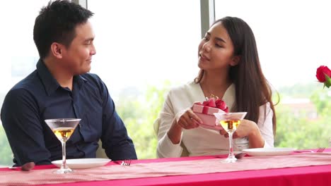 Romantic-couple-giving-gift-to-lover-at-restaurant