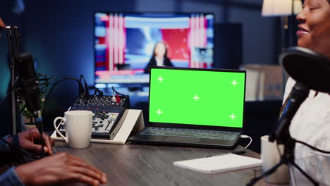 Chroma-key-notebook-next-to-analog-mixer-used-by-show-host-recording-podcast-in-studio