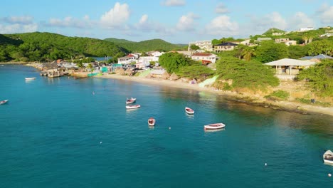 Aerial-flyover-of-red-white-fishing-boats-anchored-in-sand-off-coast-of-Boca-Sami,-Curacao