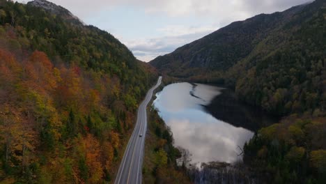A-car-is-passing-by-a-lake-surrounded-with-fall-colors-in-Upstate-New-York