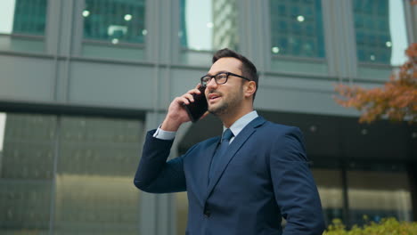 Young-business-man-talking-on-phone-outside-of-building,-close-up-slow-parallax